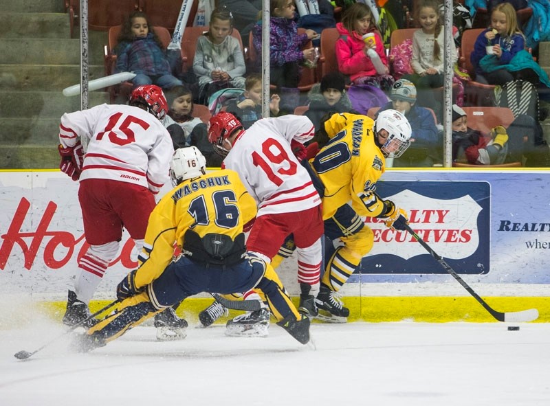 BOARD WORK â€“ Kye Buchanan of the St. Albert Gregg Distributors Sabres slips away with the puck from a gathering along the boards involving Braydon Iwaschuk of the Sabres