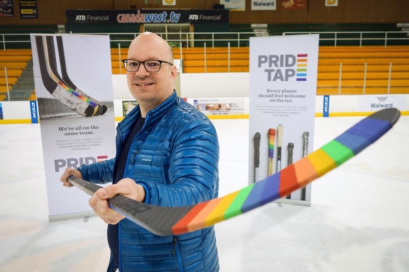 University of Alberta Prof. Kris Wells holds a hockey stick featuring a sample of Pride Tape