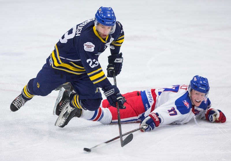 POKE CHECK &#8211; Sean Nault of the Stony Plain Flyers chips the puck away from Dan Rombough