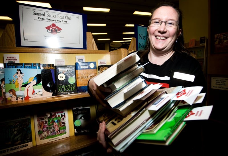 Adult programming librarian Michelle Steinhusen shows off her favourite banned book while posing in the Mugshot Photo Booth display that will be one of the features at next