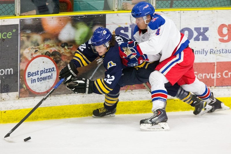 EXTRA EFFORT â€“ Matt Havens of the St. Albert Merchants plays the puck while checked into the boards by Tyler Tourangeau of the Stony Plain Flyers in Wednesday&#8217;s