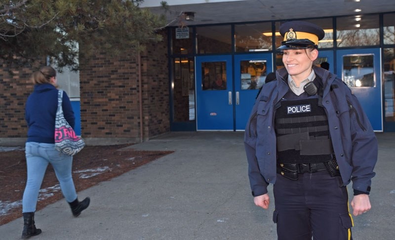 WHAT THREAT? â€“ St. Albert RCMP Cst. Jen Fraser greets students as they enter Paul Kane Monday. Fraser was one of about five officers at the school that day in response to