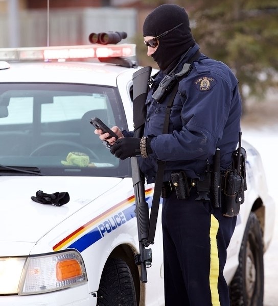 An RCMP officer uses a cellphone during the manhunt after Const. David Wynn and Auxiliary Officer Derek Bond were shot on Jan. 17