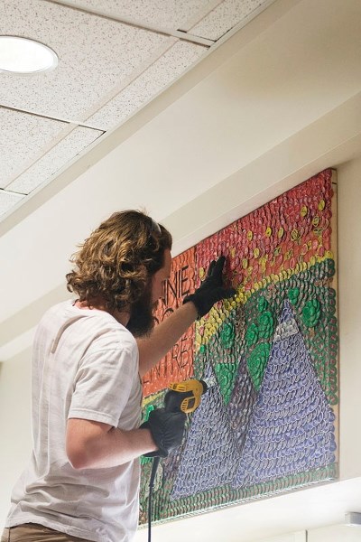Bottle cap artist Jeff Meszaros installing his newest creation at Bonnie Doon Shopping Centre at the end of February.