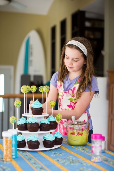 Grade 4 student Sophie Binch works on a cake pop and cupcakes for the massive bake sale Thursday April 14 at her school