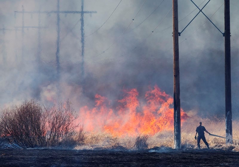 HOT STUFF — A member of the St. Albert Fire Rescue Services stares down a wall of flame as city fire departments fought to contain a large grass fire at Big Lake Thursday