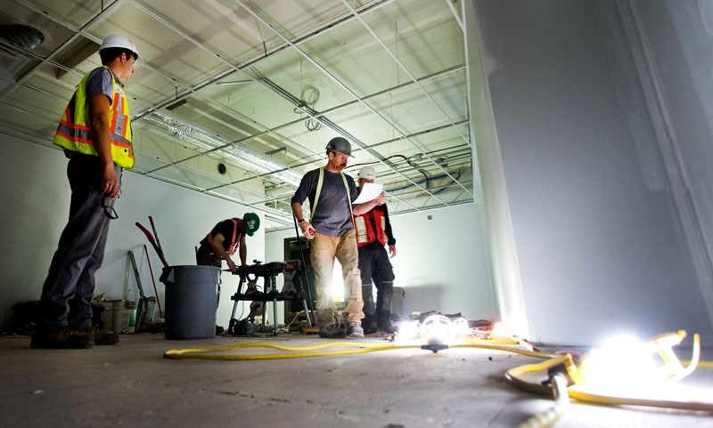 Construction workers take measurements and cut flooring at the 50 Plus Club on Wednesday April 27