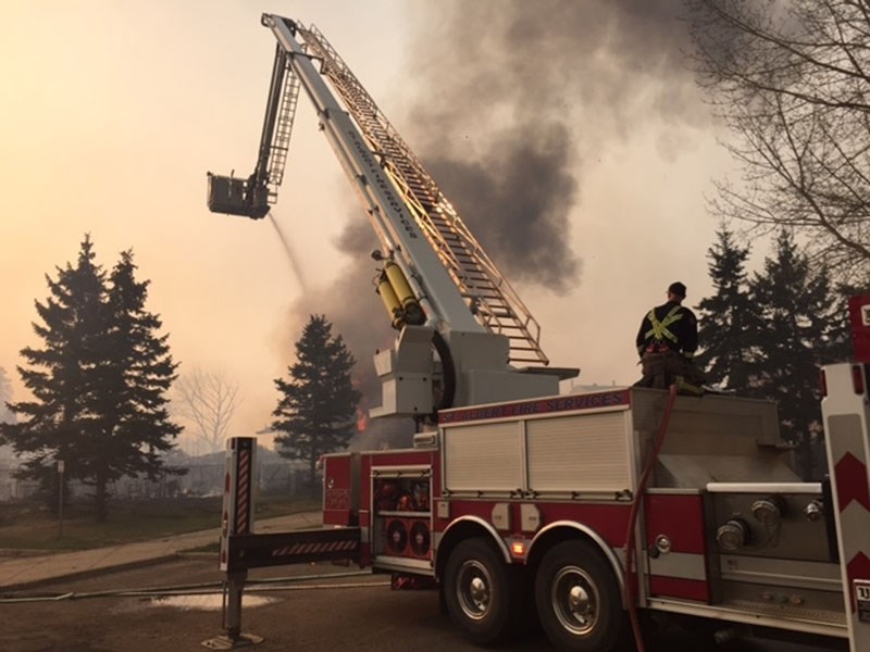 CLEANUP â€“ St. Albert firefighter Greg Harvey helps to extinguish a fire in Fort McMurray in this May 4 photo. Although the majority of the fire is now past the city
