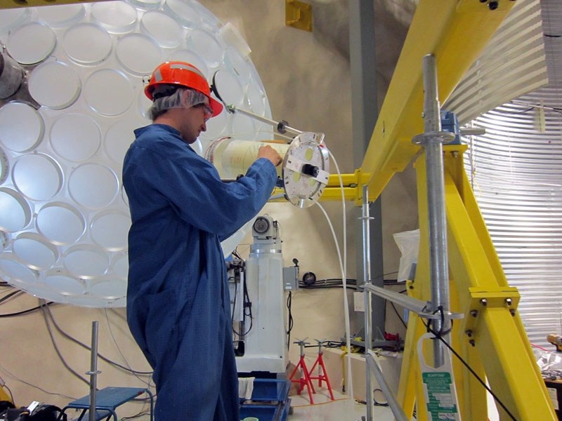 Thomas McElroy affixes a light guide to the acrylic sphere. At the end of each light guide will be a sensor detecting any energy emitted by a dark matter collision.