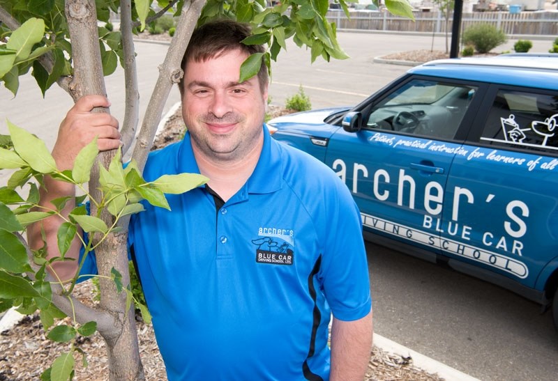 TREE CAR â€” Dominic Turgeon of Archer&#8217;s Blue Car hugs a tree outside the Gazette office. Turgeon&#8217;s business buys carbon credits through the Carbon Farmer to