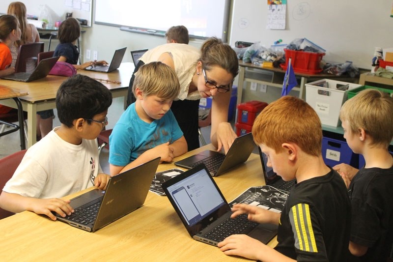 Patricia Toth helps students work through a coding application from a Bitsbox book in a workshop on June 23.