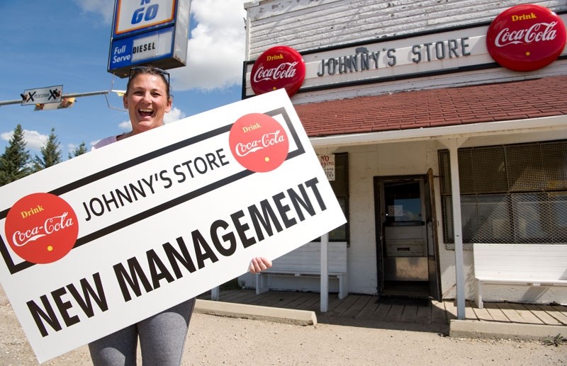RE-OPEN FOR BUSINESS â€“ Store operator Carolyn MacPherson shows off the sign that greeted visitors to Johnny&#8217;s Store Monday. The famous store reopened for business for 