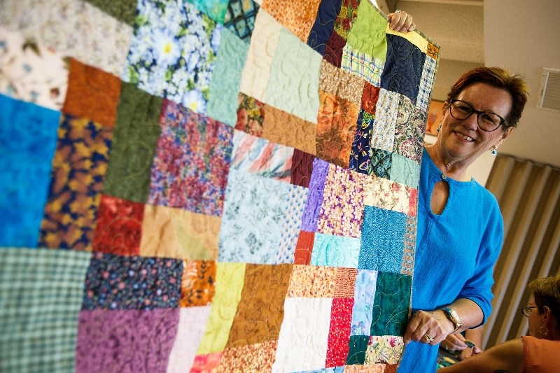 Wendy Hilton of the St. Albert Quilters&#8217; Guild shows off a finished quilt that will be donated to charity.