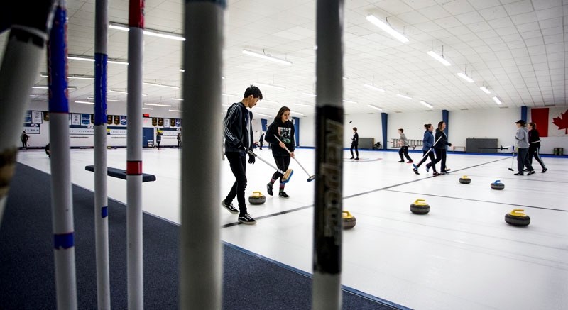 ROCKING THE ICE â€“ Jacob Pickering and Cassandra Siwiec-Hlewko of the Paul Kane Blues are framed between a pair of brooms while following a rock down the ice at the Jasper