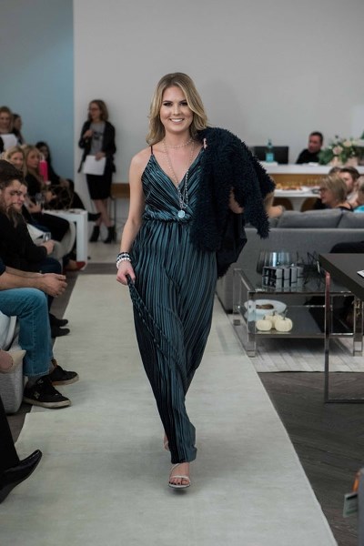 Katie Radmanovich parades down the fashion runway wearing a Who Cares Wear evening gown with a navy blue faux fur jacket. She was one of the models in a charity fashion show
