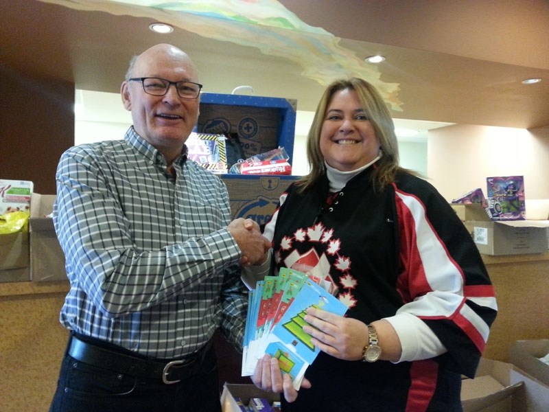 Optimist Club of St. Albert president Glen Kreller presents St. Albert Kinettes Kim Bedry with Best Buy gift cards. The needed donations will be placed as gifts in some of