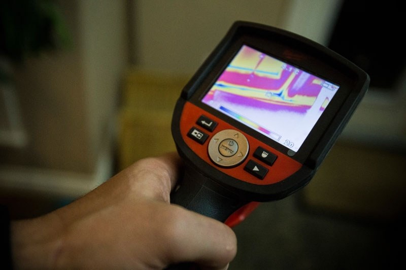 COLD SPOT â€“ Thomas Barr spots an unusually cold corner in the back door of Leclair&#8217;s home using a thermal camera. While the door reads 20 C