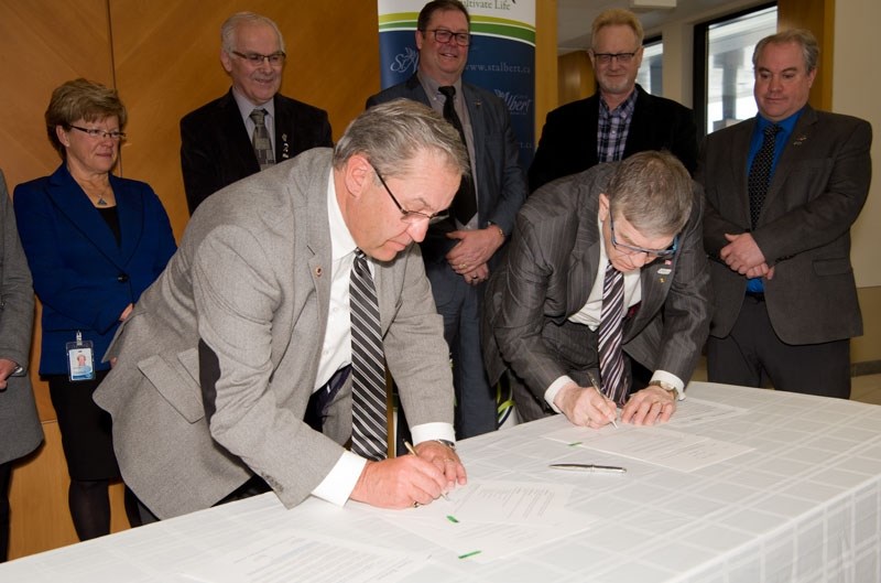 ANNEXATION AGREEMENT — Mayors Tom Flynn and Nolan Crouse sign a memorandum Tuesday at the Sturgeon County office. The memo commits their respective governments to negotiating 