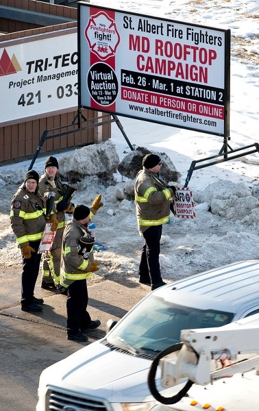 Firefighters encourage passing motorists to donate to the St. Albert Fire Fighters for Muscular Dystrophy Rooftop Campout campaign outside Firehall #2 on Boudreau Rd. on