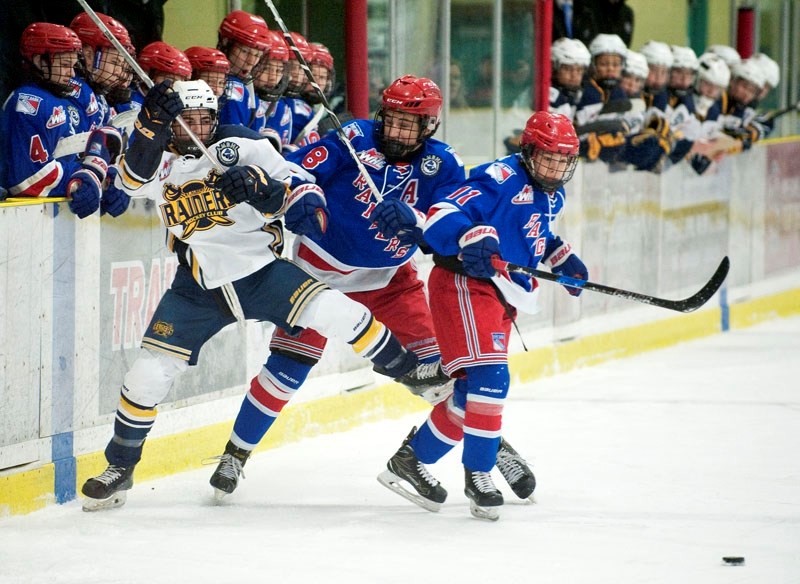 CHECKERED – Robert Kincaid of the St. Albert Gregg Distributors Sabres is knocked askew by Noah Boyko of the Fort Saskatchewan Rangers as Olen Zellweger goes for the puck in
