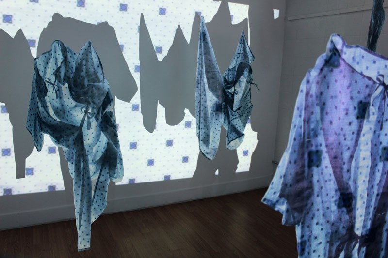 Printmaker Darian Goldin Stahl offers viewers her interpretation of her sister&#8217;s multiple sclerosis examinations through hospital gowns with MRI text projected onto