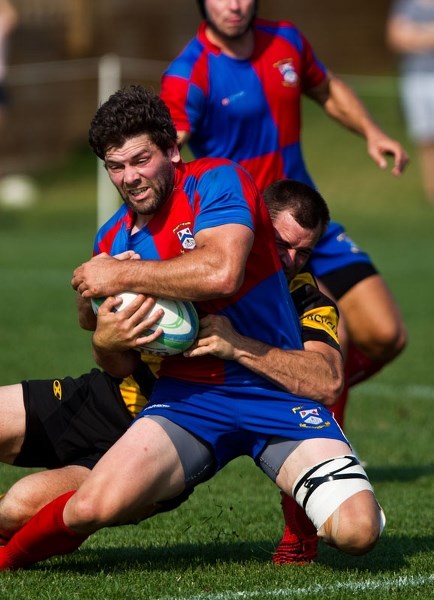 HANGING ON – Adam Bontus is brought down to his knees by a tackler in Saturday&#8217;s premier men&#8217;s match between the host St. Albert Rugby Football Club and the
