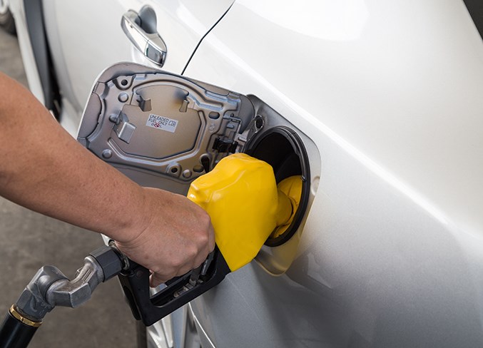 Hand with nozzle fueling unleaded gasoline into car