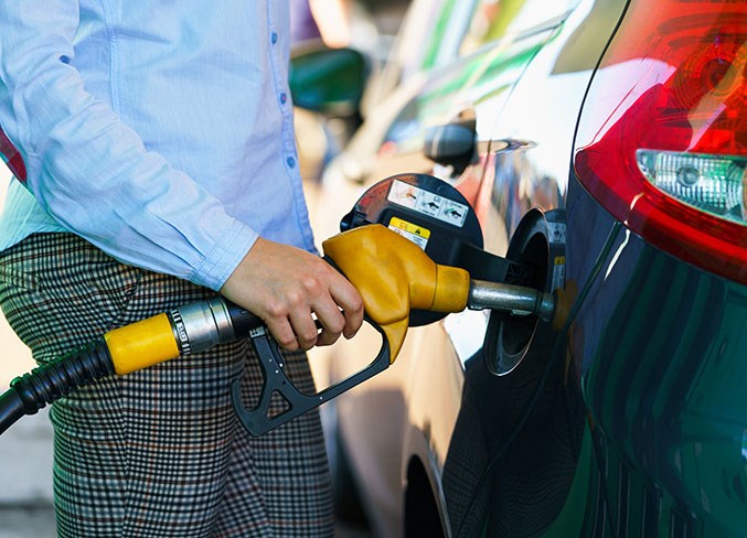 Woman fills petrol into the car at a gas station