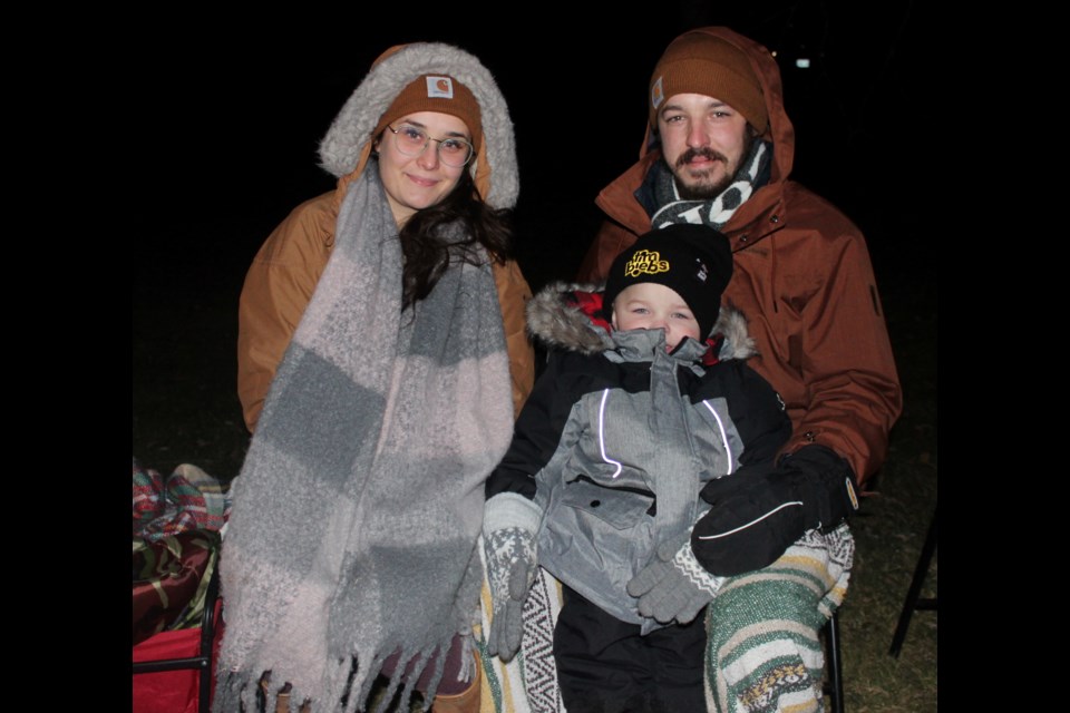 Sarah Killeleagh and Brayden Kalbfleisch, with Miles, middle, enjoy the parade of lights on Sunday night. 