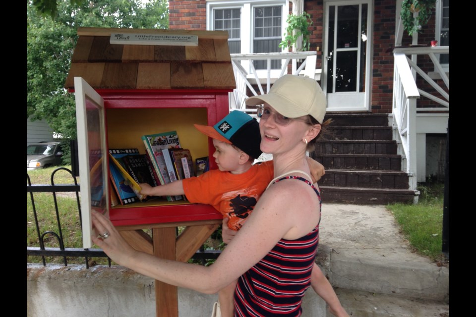 Lauren Foy and her son Ziggy using the Eyre Street Little Free Library. (Supplied/Jessica Watts)
