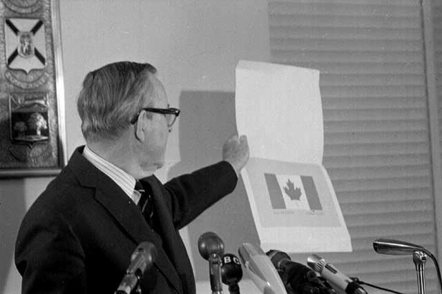 Prime Minister Lester B. Pearson unveils the familiar maple leaf with red bars design. Image: Library and Archives Canada