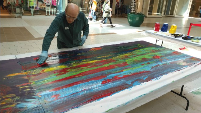 North Bay’s Ray Kazlauskas was the first to try his hand at Myths and Mirrors’ collaborative painting project at the New Sudbury Centre Saturday. Photo by Jonathan Migneault.