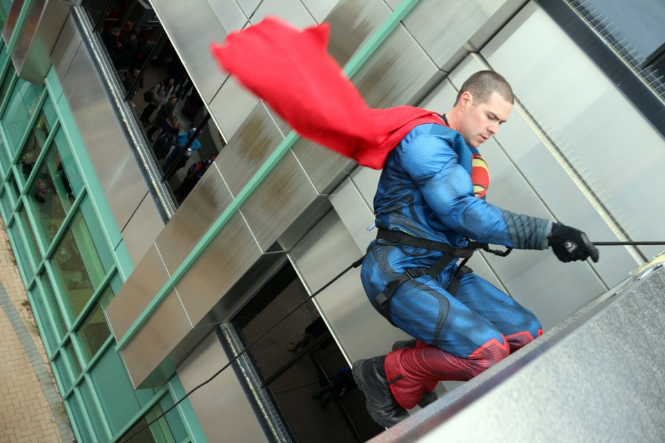 Cape flying, Superman swings out over the edge of Health Sciences North. Photo by Heather Green-Oliver