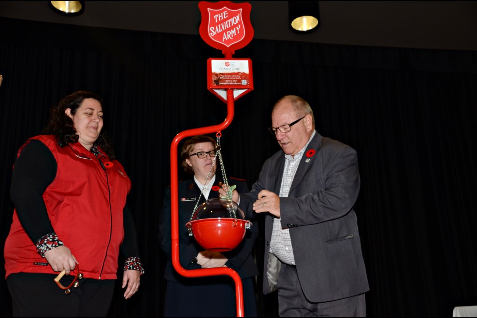 Caroline Lewis and Capt. Anney Summerfield look on as Mayor Brian Bigger makes the first donation to the Christmas kettle campaign. (Marg Seregelyi/MargsPhotography.com)
