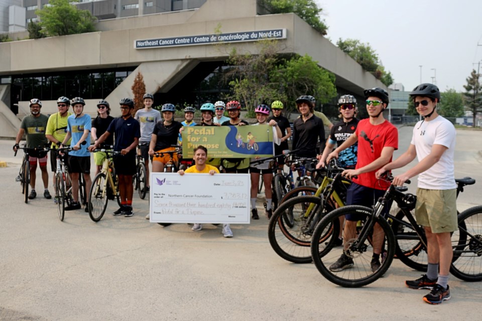 The 21 participants in Pedal for a Purpose on June 3, 2023, in Sudbury gather around Kristofer Cacciotti, the ommunity engagement and events specialist for the Northern Cancer Foundation, who holds a big cheque showing the total amount raise for the event: $7,383.