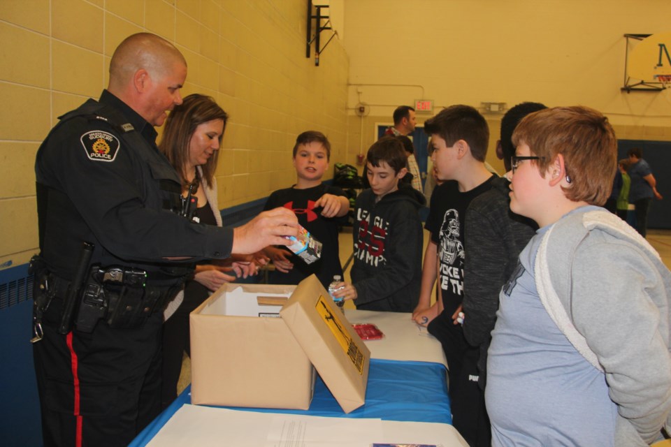 Marc Savignac from Greater Sudbury Police Service's RURAL community response unit and search and rescue, and Suzette Belanger, administrative assistant to the deputy fire chiefs with the City of Greater Sudbury, work with Carl A. Nesbitt Public School students on an emergency preparedness kit exercise May 6. (Supplied)
