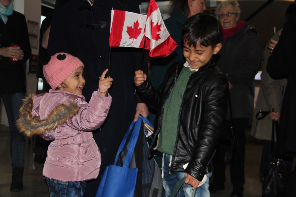 The fifth family of Syrian refugees to settle in Greater Sudbury arrived at the Sudbury Airport Dec. 7. Tuqa Alyousef, 3, and her brother Muhi Eddin Alyousef, 6, play with Canadian flags given to them by well-wishers upon their arrival. Photo by Heidi Ulrichsen