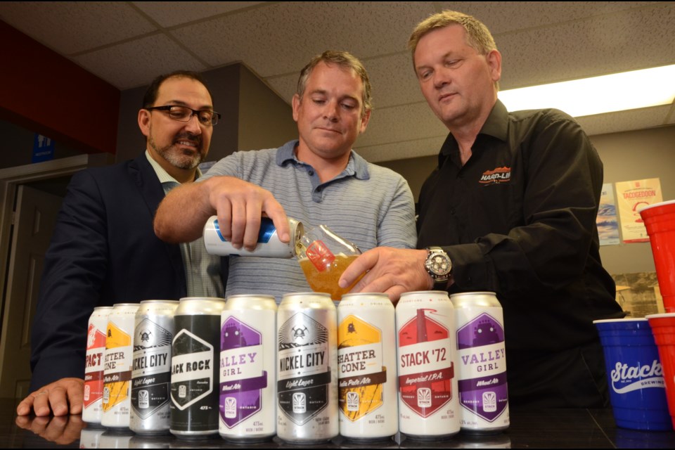 Stack Brewing owner Shawn Mailloux, centre, pours a glass of Saturday Night with Sudbury MPP Glenn Thibeault, left, and Hard-Line Solutions president Walter Siggelow following a Northern Ontario Heritage Fund Corporation funding announcement on Friday. Photo by Arron Pickard