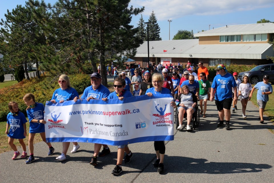 Mayor Brian Bigger joins supporters in holding the Parkinson Superwalk banner, leading the group of walkers to the track at Delki Dozzi Park on Sept. 10, 2022. 
