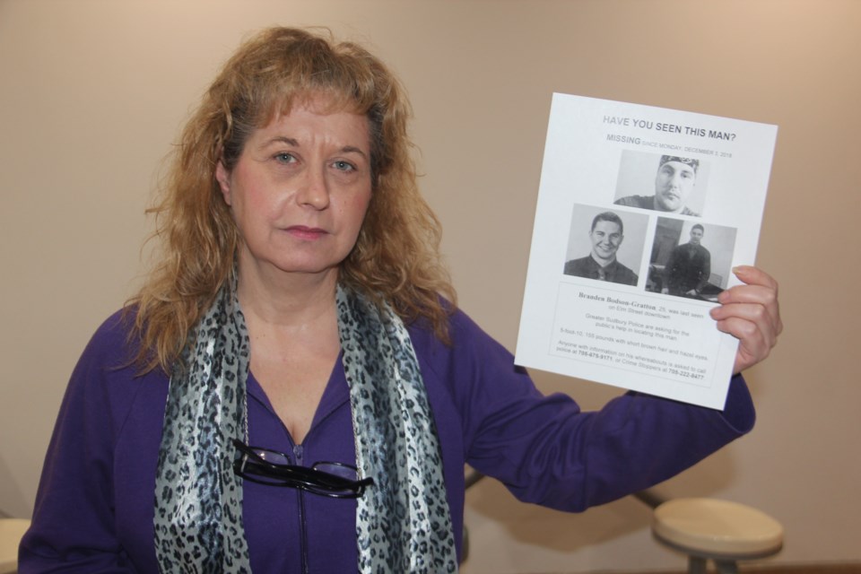 Diane Gratton shows off a poster with images of her son, Branden Bodson-Gratten, that volunteers have been putting up around the city. (Heidi Ulrichsen/Sudbury.com)