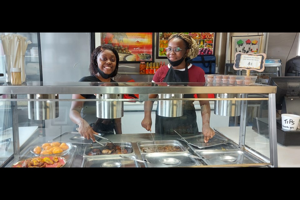 Owner Nickesha Simpson shows the serving station at Flames with staff member and student Wawa Carmene. 