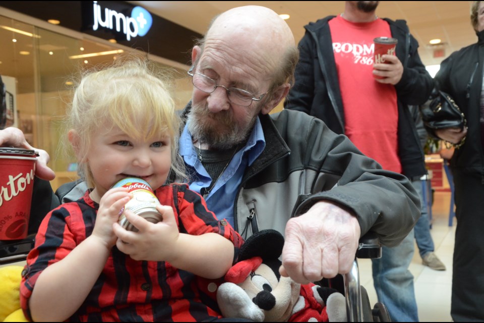 Payton Burton, 3, is the great niece of Edgar Burton, and she sits with Edgar's brother, Roger Burton, as they wait to donate a can of soup at the launch of the annual Edgar Burton Food Drive on Nov. 17 at the New Sudbury Shopping Centre. Photo by Arron Pickard.