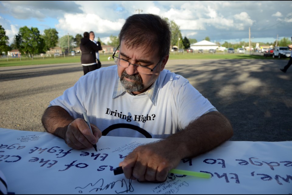Gilles Lefebvre signs a banner prior to the start of the sixth memorial walk honouring the memories of Jazmine Houle, Steven Philippe and Caitlin Jelley. (Arron Pickard/Sudbury.com)