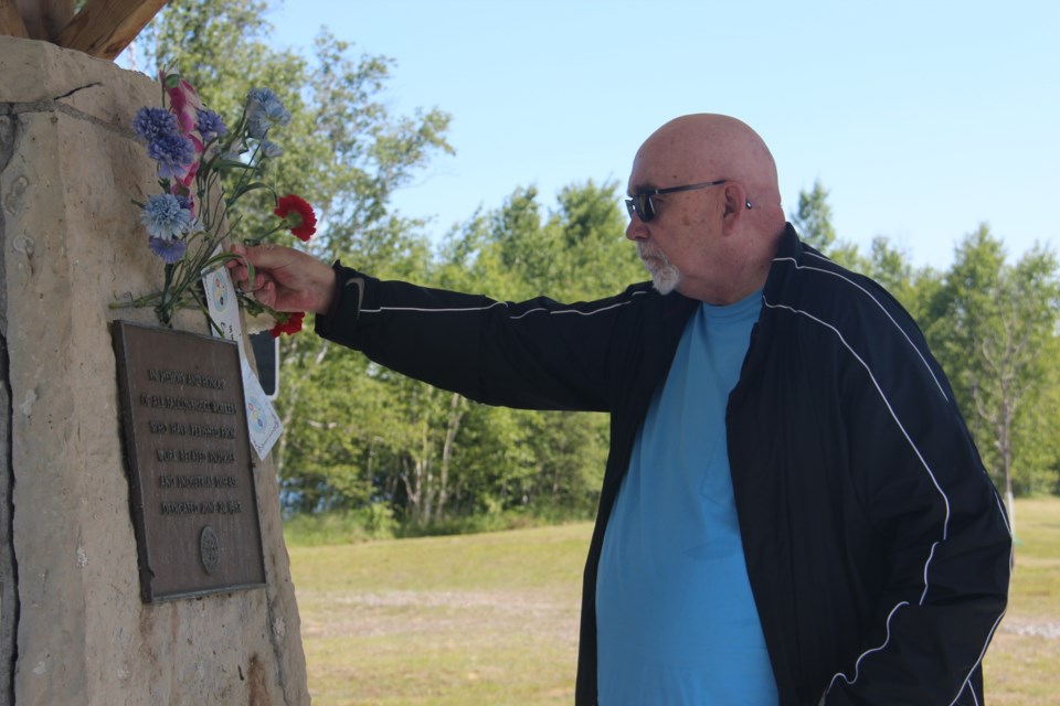 Falconbridge Ltd. retiree Brad Anderson places a carnation at the memorial at Mine Mill's campground on Richard Lake as part of the Workers' Memorial Day ceremony. (Heidi Ulrichsen/Sudbury.com)
