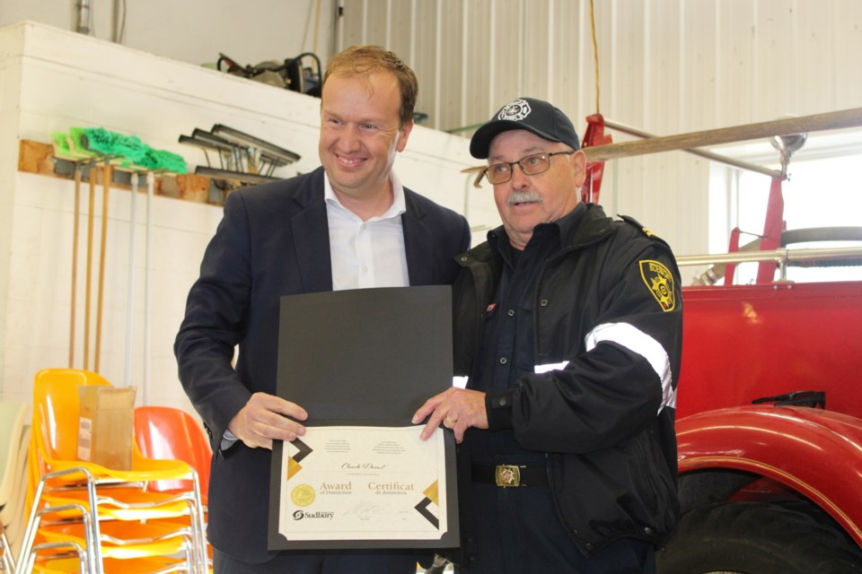 Mayor Paul Lefebvre hands Claude Daoust an award of distinction at the Chelmsford Fire Station on May 24, noting his 50 years of volunteer service.