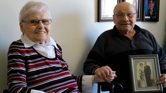 Gottfried Adler gazes lovingly at his wife of 67 years, Hildegard, who smiles happily into the camera. The once-separated hold hands in their room at Finlandia Village’s Hoivakoti residence, finally reunited after half a year apart due to a health-care system that does not prioritize couples when accessing long-term care. (Allana McDougall/Sudbury.com)