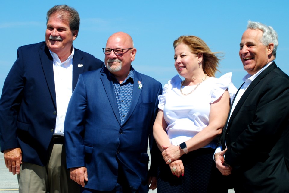 Greater Sudbury Airport CAO Todd Tripp, Mayor Brian Bigger, Sudbury Liberal MP Viviane Lapointe and Nickel Belt Liberal MP Marc Serré pose for a photo on a runway at the Greater Sudbury Airport on June 28 following a federal funding announcement. 