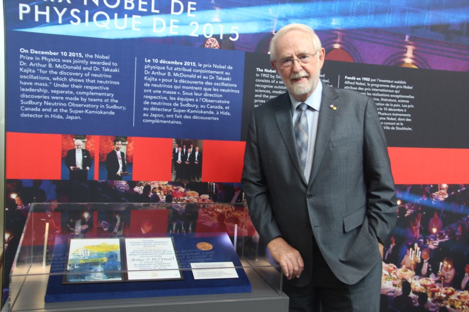 Art McDonald poses in front of the New Eyes on the Universe exhibit, which features a section on his Nobel laureate win. (Heidi Ulrichsen/Sudbury.com)