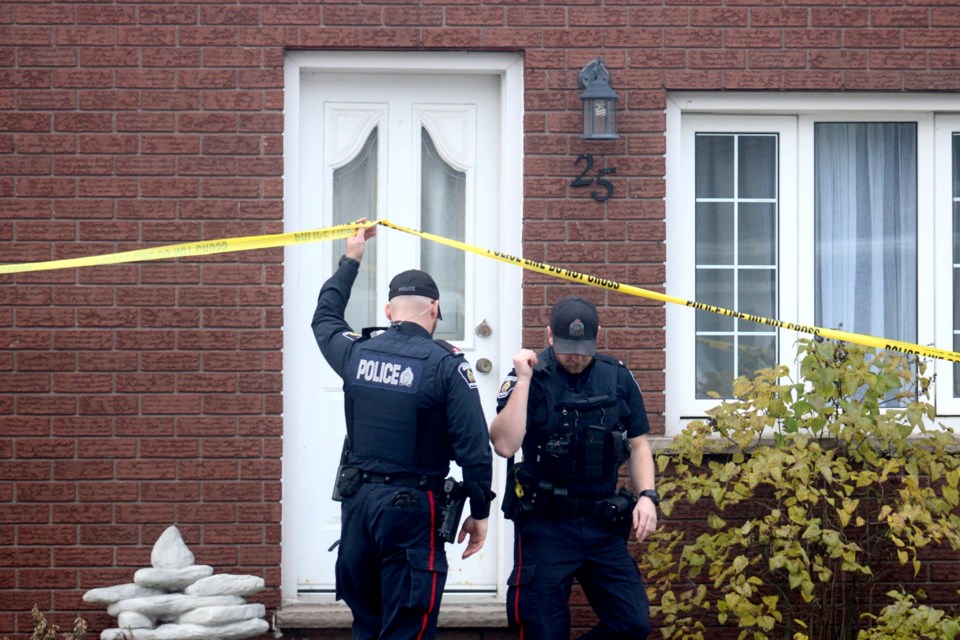 Police are seen investigating the scene where three people were found dead in Coniston on Sunday at a home on Caruso Street.