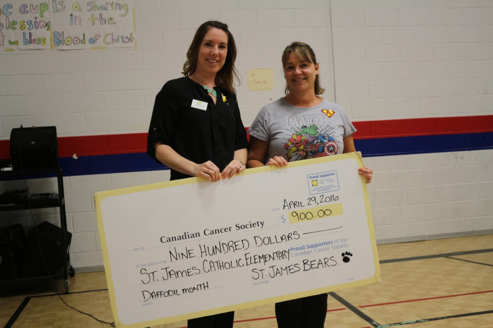 Lindsey Jones, volunteer engagement coordinator for the Canadian Cancer Society, and Tammy Lanci, teacher at St. James Catholic Elementary School, reveal the $900 cheque raised during the schools daffodil fundraiser. Photo by Patrick Demers.